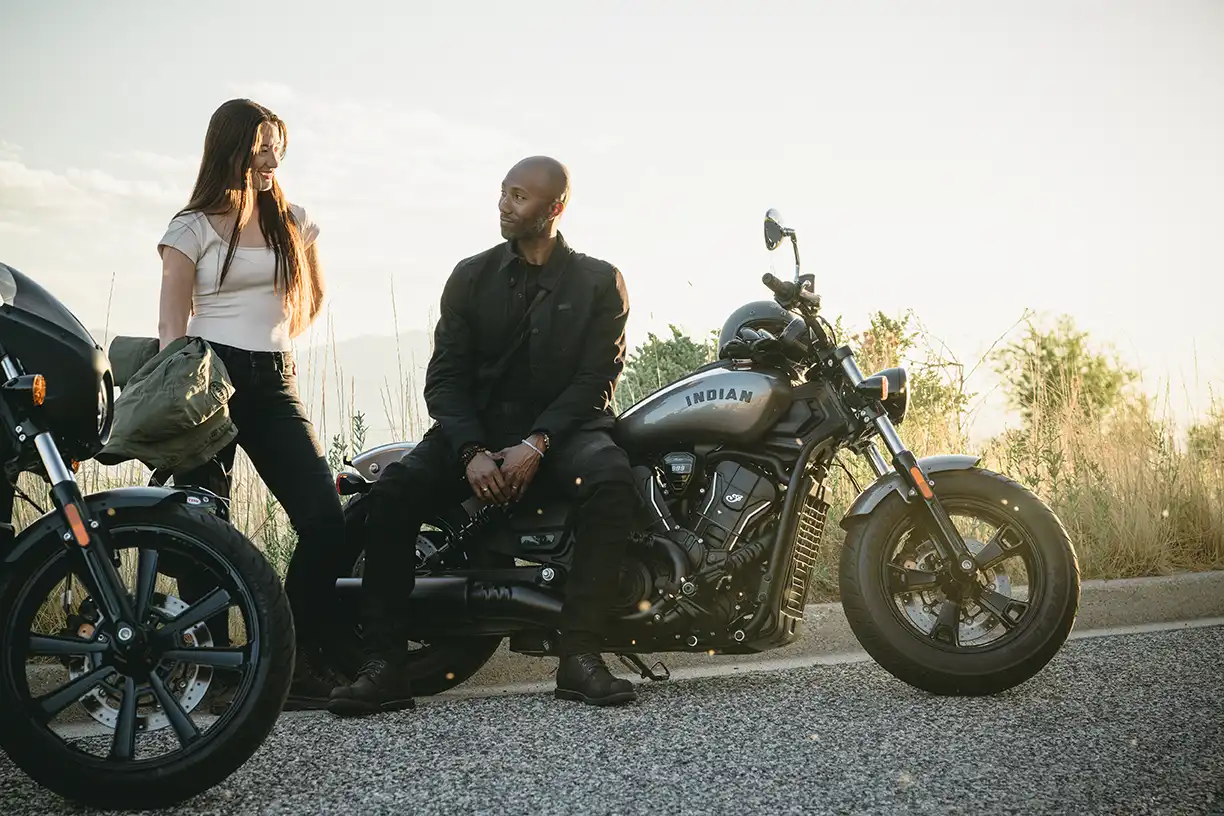 Zwei Personen sprechen auf einer Indian Scout Sixty miteinander